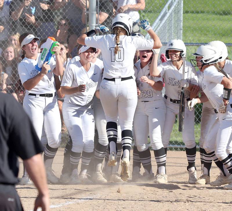 Kaneland's Emily Olp jumps onto home plate and is greeted by her celebrating teammates after she hit a 3-run homer that put the Knights up 3-0 on Belvedere North late in the game Friday, June 3, 2022, during their IHSA Class 3A Sectional final game at Sycamore High School.