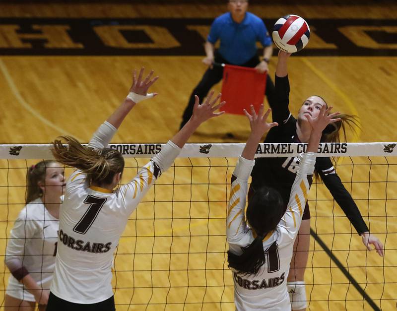 Prairie Ridge's Addy Grider (right) hits the ball over the block of Carmel's Liv Johnson (left) and Charlotte Shepherd (center) during the IHSA Class 3A Carmel Sectional championship volleyball match on Thursday, Nov. 6, 2025, at Carmel High School, in Mundelein.