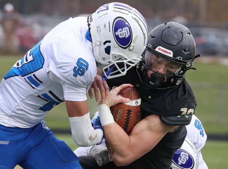 Sycamore's Burke Gautcher takes a hit from St. Francis' Isaac Saldana Saturday, Nov. 16, 2024, during their Class 5A quarterfinal game at Sycamore High School.