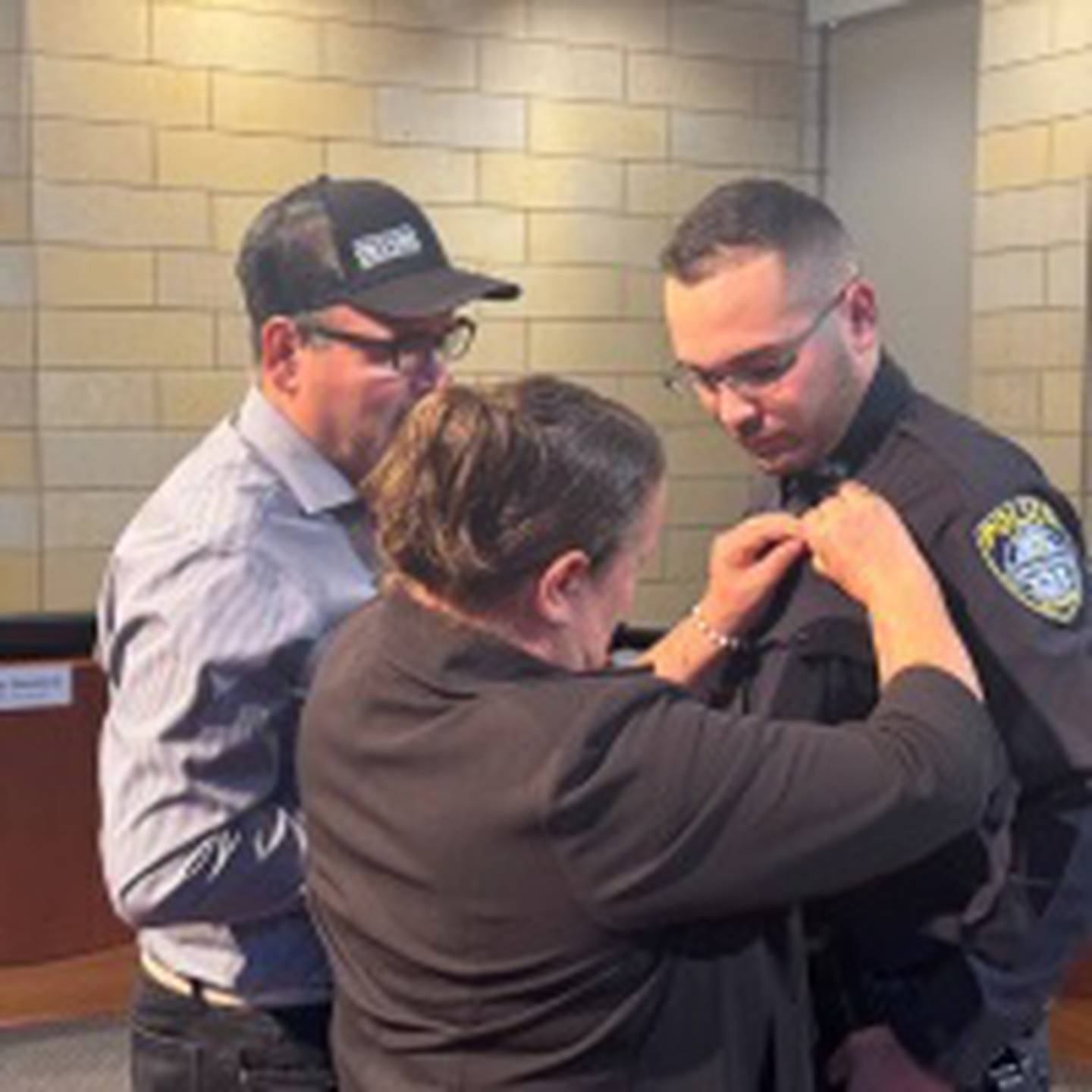 The parents of Officer Jovani Chaidez pin him with his badge as a new member of the village of Montgomery Police Department on Sept. 8, 2025.