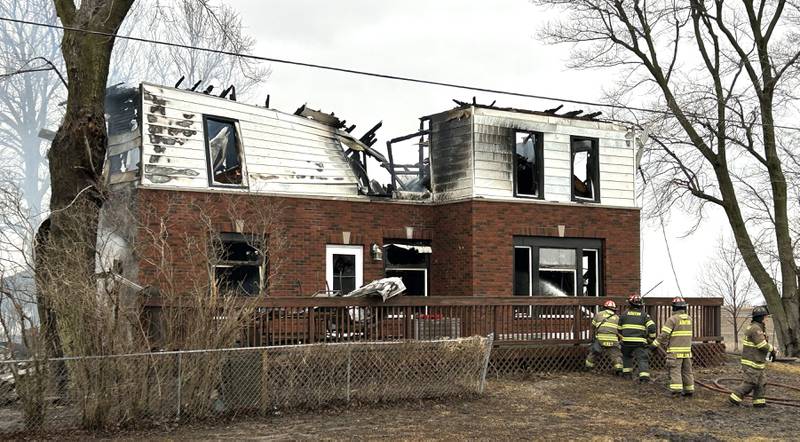 Firefighters sparay water on flames at a house fire at 8423 East Illinois route 38 on the afternoon of Wednesday, March 5, 2025. A portion of the state highway, between Chana Road and Brooklyn Road, was closed to allow crews to bring in tankers to help extinguish the blaze. Firefighters were faced with temperatures in the 30s and a strong, frigid wind out of the northwest that fueled flames at the home, located on the south side of the highway.