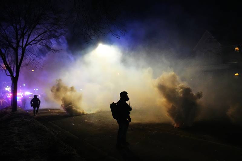 Law enforcement officers stand amid tear gas at the scene of a reported shooting Wednesday, Jan. 14, 2026, in Minneapolis. (AP Photo/Adam Gray)