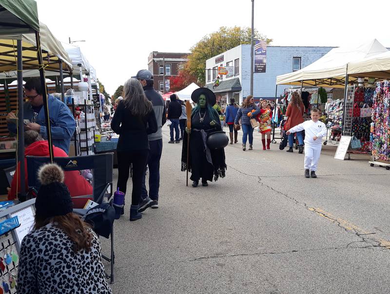 Visitors, including "a witch," make their way along Walnut Street in Oglesby through vendor shops Saturday, Oct. 16, 2022, during Harvest Fest.