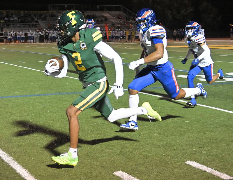 Fremd’s Marquan Brewster sprints down the sidelines for a touchdown after a catch as Hoffman Estates’ Nate Cleveland chases him in a football game in Palatine on Friday, Sept. 27, 2024.