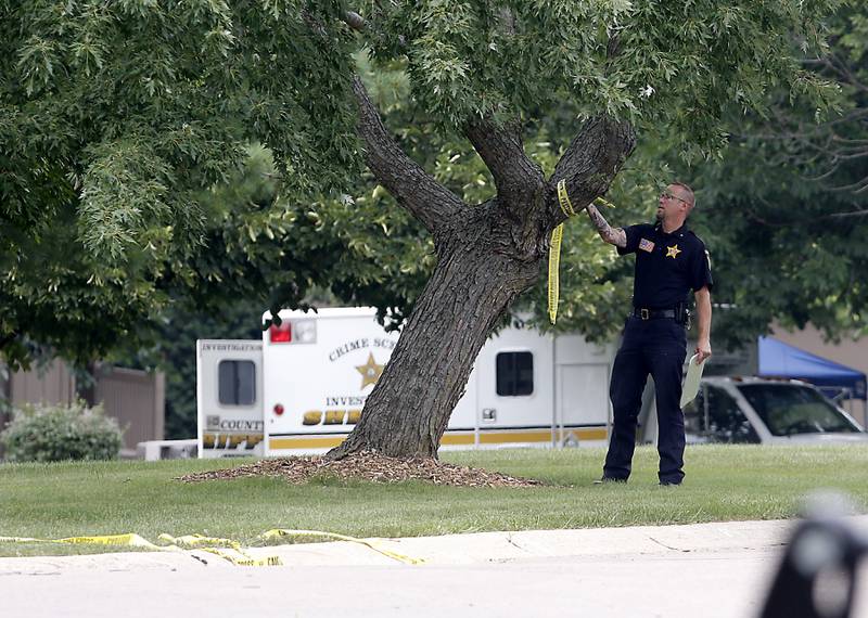 A McHenry County Sheriff's officer removes some police tape at the scene of a domestic incident in which four people were killed on Wednesday Aug. 9, 2023, in the 5800 block of Wild Plum Road in unincorporated Crystal Lake. Police said they were family members.
