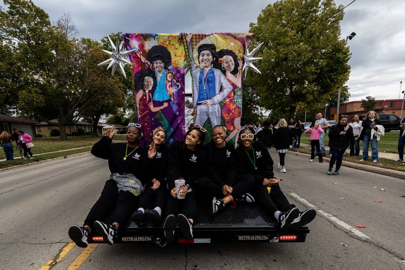 Members of Joliet West’s cheer team ride along Glenwood Ave. in Joliet during the Joliet West homecoming parade on Oct. 10, 2025.