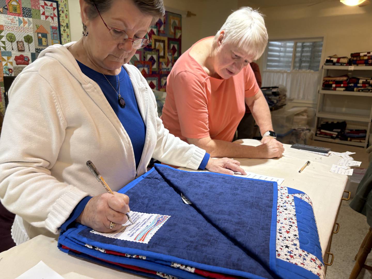 Bev Kenny and Joan Ausbury label a quilt for a veteran Oct. 31, 2024 in Huntley.