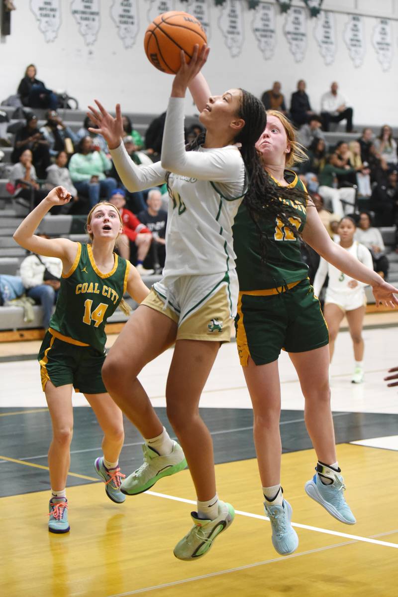 Bishop McNamara's Trinitee Thompson, center, takes a shot between Coal City's Riley Walker, left, and Jori Tucker during a game at Bishop McNamara Tuesday, Nov. 25, 2025.