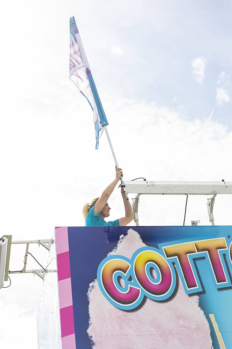 When the cotton candy flag flies you know it’s Petunia time as seen Monday, July 1, 2024 in Dixon. Gypsy Jones places the flag atop a food stand as prep for the carnival is in full swing.