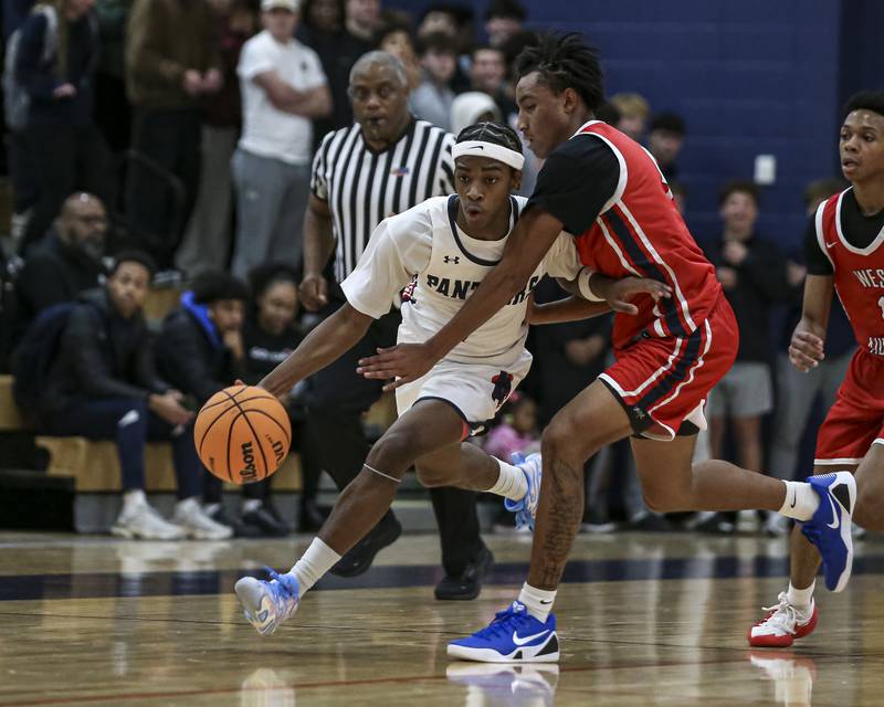 Oswego's TJ Wilson (1) drives past the defense of West Aurora's Antonio Higgins (4) during their basketball game between West Aurora at Oswego Monday, Nov 24, 2025 in Oswego.