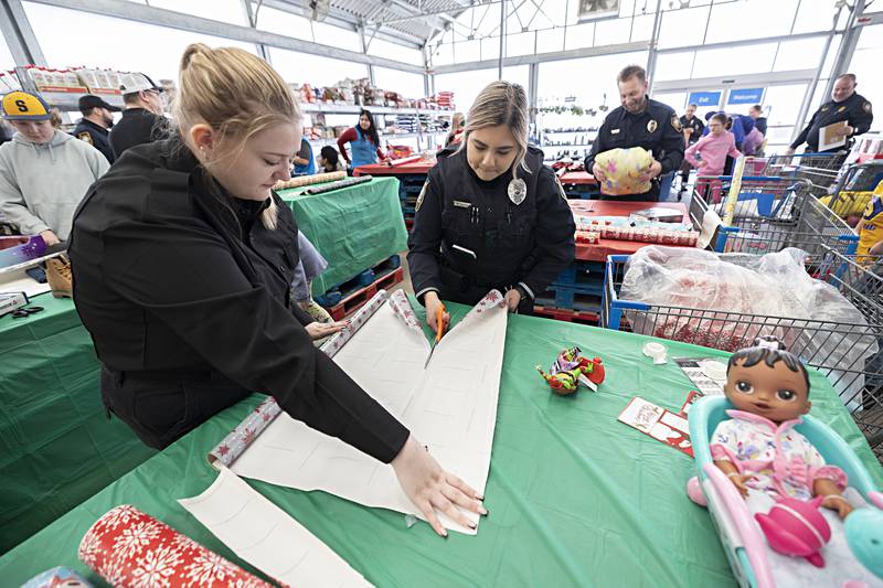 Police explorer Natalie Gaulke (left) and new Sterling police officer Joselyn Garcia wrap gifts Saturday, Dec. 9, 2023 at Sterling's Walmart as part of the department's Shop with a Cop program.