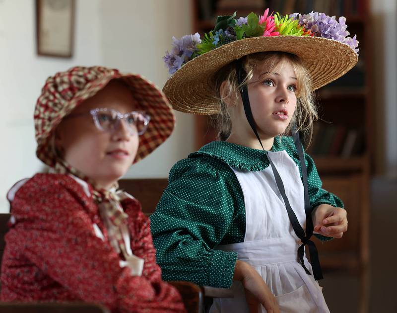 Southeast Elementary School third graders Brynlee Monney (front) and Cece Zantout listen to their teacher Tuesday, Nov. 4, 2025, during a field trip to North Grove School, a one-room schoolhouse from 1878 in Sycamore.