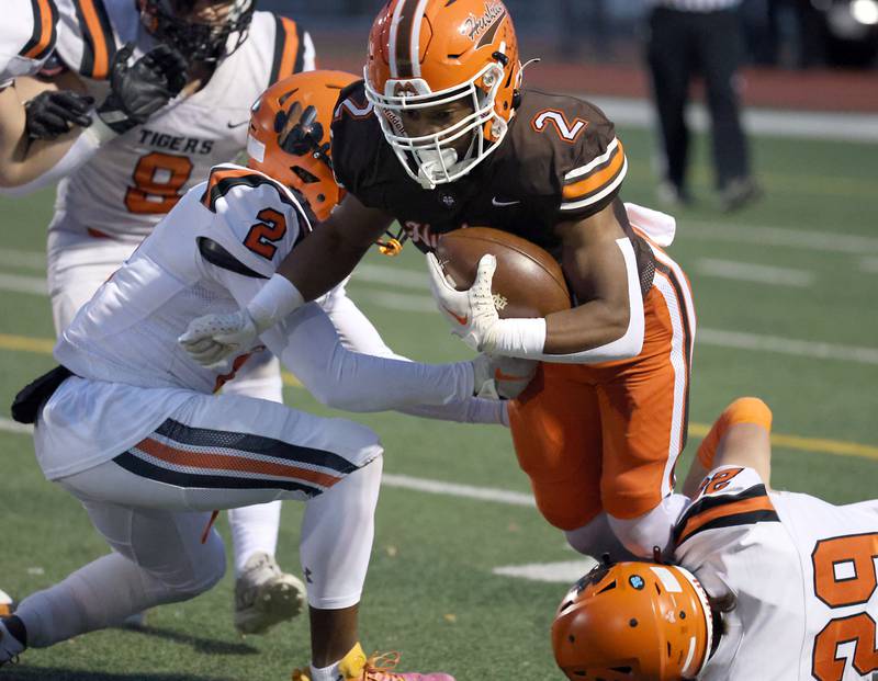 Hersey's Nasir Mckenzie, (2) is wrapped up by Wheaton Warrenville South's Connor Sliwa (2) and Lucas Rossini (29) during the IHSA Class 7A playoffs Saturday October 28, 2023 in Arlington Heights.