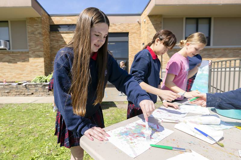 Emma Dempsey, a sixth grader at St. Mary’s in Dixon, rakes a fork across her work to create a unique piece of art Friday, May 9, 2025.