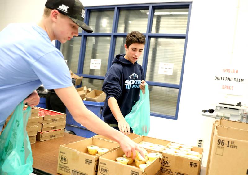 Downers Grove South High School freshmen Luke Conley (left) and Joseph Conyer pack bags of food as part of the Blessings in a Backpack program on Monday, Nov. 13, 2023. The program will provide meals for 200 food insecure students in Downers Grove Grade School District 58 who won't have access to school meals during the upcoming Thanksgiving break.