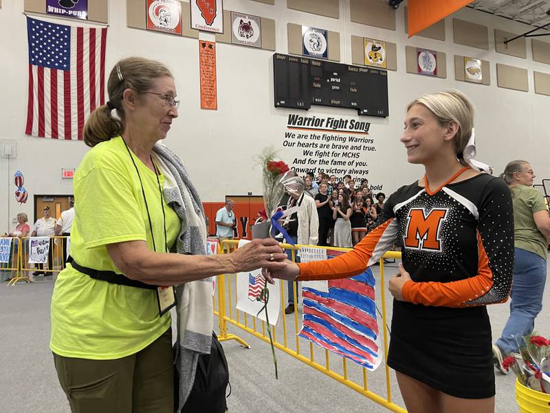 Lee Ellington, a member of the Navy, receives a rose from senior cheerleader Morgan Nosalik on Sunday, Aug. 28, 2022. Ellington was one of 51 veterans who went on the Honor Flight over the weekend to visit war memorials in Washington D.C. and were welcomed home at McHenry High School.