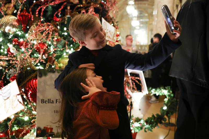 Santo Nikolakopoulos, 8 years-old, takes a photo with his sister Mia, 4 years-old, in front of the Rialto Christmas Tree at the A Very Rialto Christmas show on Monday, November 21st in Joliet.