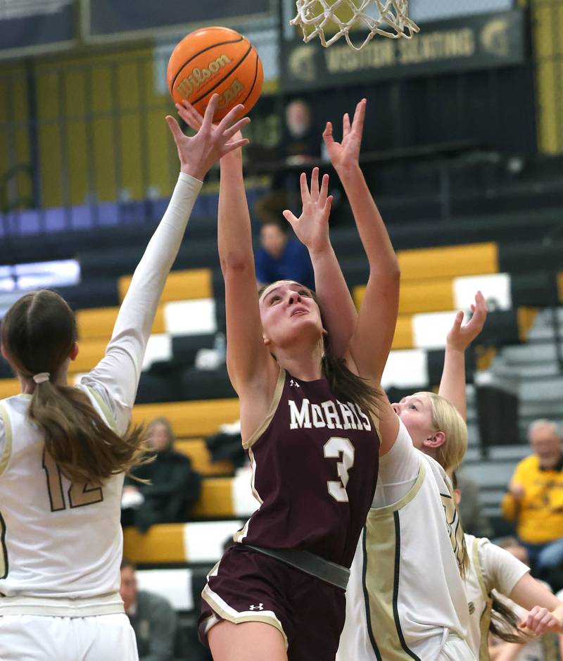 Morris' Lily Hansen goes to the basket between two Sycamore defenders during their game Tuesday, Jan. 13, 2026, at Sycamore High School.