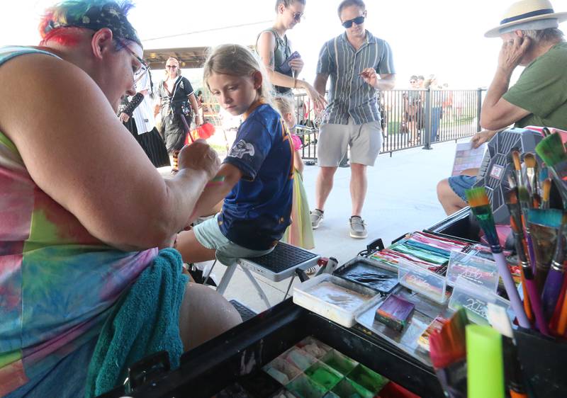 Diane Martin of Crazy Cat Lady Face Painting, paints the arm of Elise Theisinger during the Illinois Valley Pistol Shrimp Halloween in July on Wednesday, July 23, 2025 at Schweickert Stadium in Peru. The event featured a Trick or Treat Scavenger Hunt presented by Peru Federal Savings Bank, Pregame Performance from the Hocus Pocus Hags and a kids costume parade.