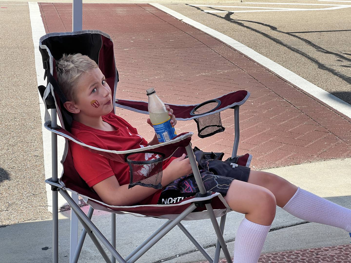 Cayson Oltman, the grandson of Cassie's Popcorn Stand owner, Cassie Oltman, sits in a chair near his family's business on July 25, 2024.