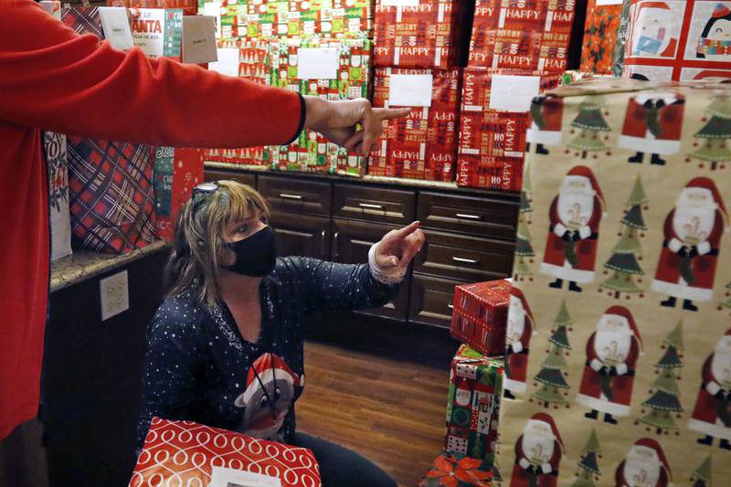 Jacci Richards of Fischer Outreach Group, bottom, and Mary Wood of Campion Curran Law look through the presents to hand out to residents during an adopt-a-grandparent gift event at Gable Point Senior Housing on Wednesday, Dec. 22, 2021, in Crystal Lake.