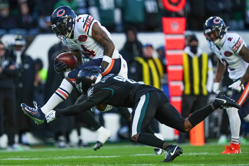 Chicago Bears running back D'Andre Swift (4), top, is tripped up by Philadelphia Eagles cornerback Adoree' Jackson (8) during the first half of an NFL football game, Friday, Nov. 28, 2025, in Philadelphia. (AP Photo/Matt Rourke)