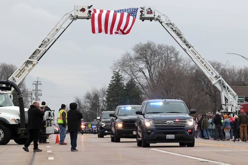 The processional to Butala Funeral Home honoring DeKalb County Sheriff’s Deputy Christina Musil goes under ladder trucks from the DeKalb and Shabbona Fire Departments Monday, April 1, 2024, on DeKalb Avenue in Sycamore. Musil, 35, was killed Thursday while on duty after a truck rear-ended her police vehicle in Waterman.