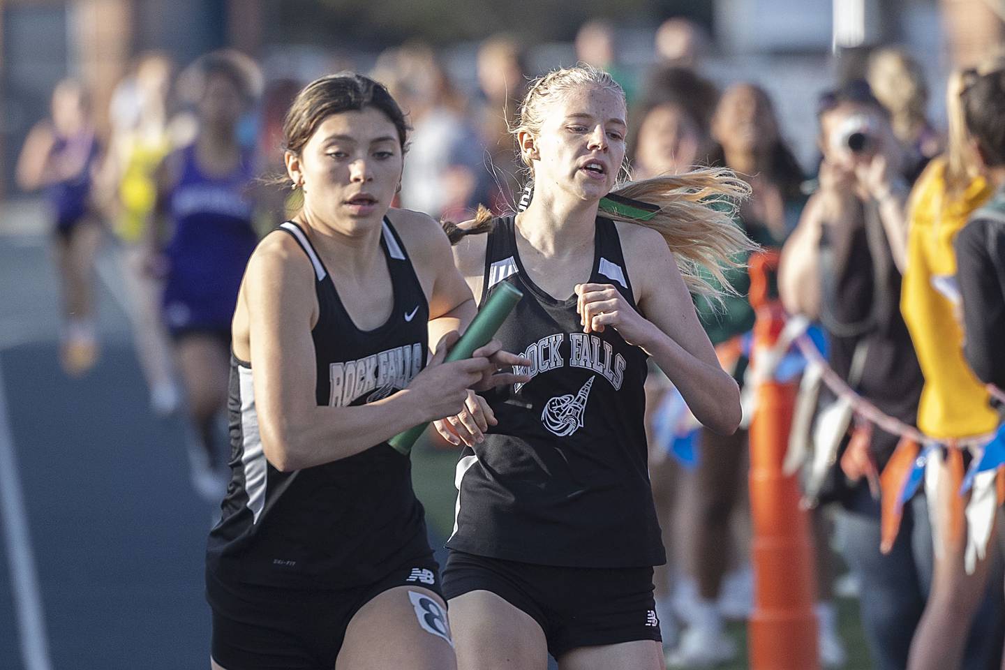 Rock Falls’ Gracie Rippy (left) takes the baton from Kat Scott in the 4x800 Thursday, April 27, 2023  at the Sterling Night Relays.