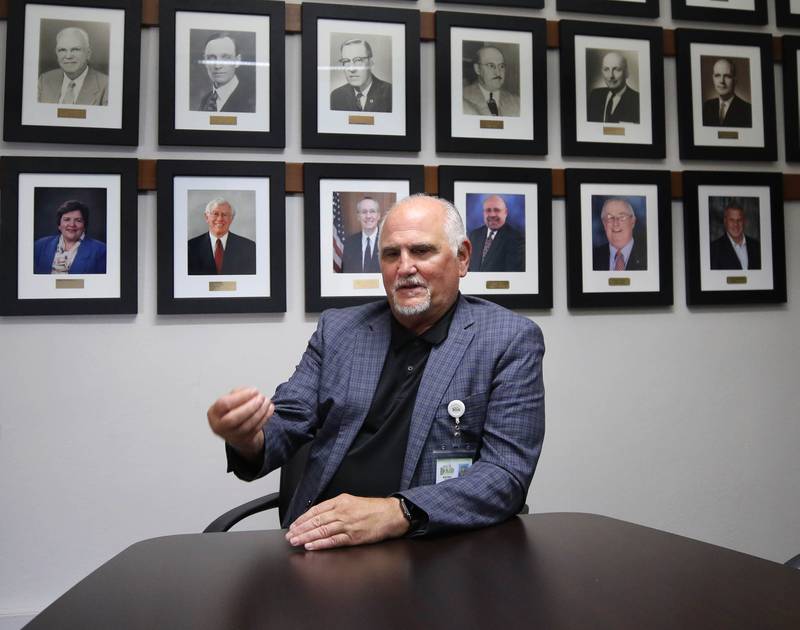 Bradley Hoey, flanked by portraits of past DeKalb mayors, talks Tuesday, Aug. 19, 2025, about how it has gone since he was first sworn into office as DeKalb City Clerk nearly 100 days ago.