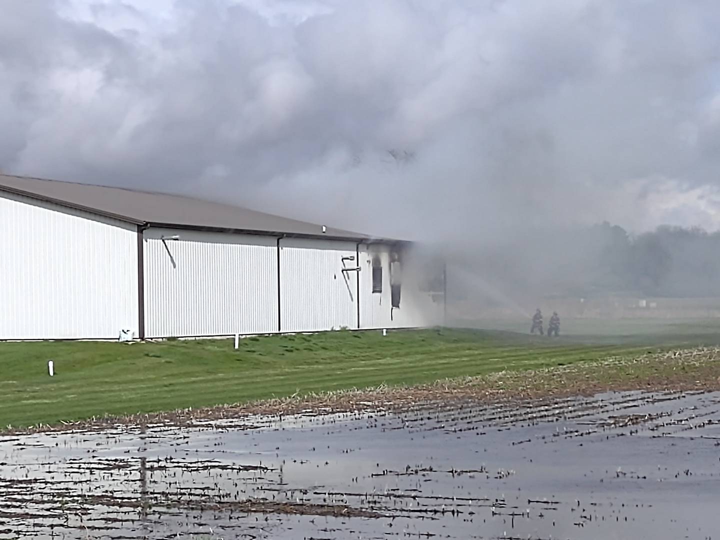 Firefighters spray water Thursday, April 4, 2024, as smoke comes from the back of a warehouse at MTC Voyager Corp. on Titanium Drive in Ottawa.