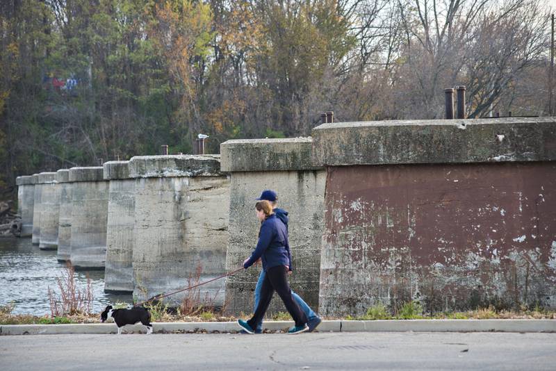 FILE: Pedestrians walk past old railroad pylons that cross the Rock River at Page Park in Dixon Tuesday, Nov. 16, 2021. Project Rock, construction of a pedestrian bridge across the old railroad structures, will begin in 2025.