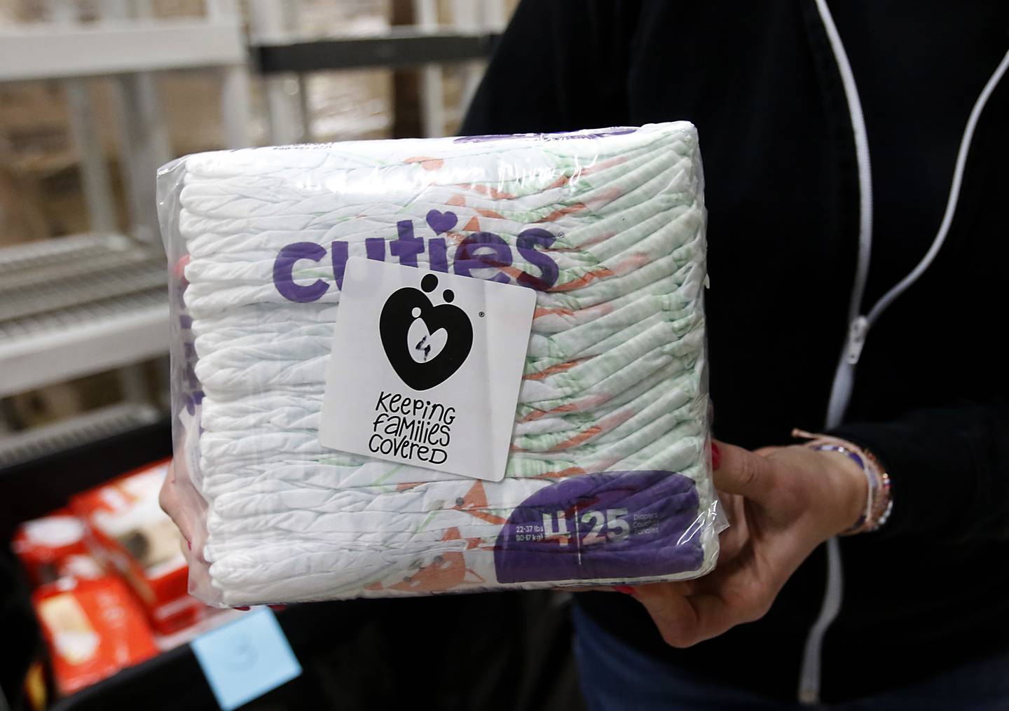 Ann Marie Mathis, the founder and CEO of Keeping Families Covered, holds a package of diapers that the nonprofit distributes on Monday, Jan. 24, 2023, inside the new facility at 4138 W. Orleans St. in McHenry. Keeping Families Covered has taken over for the Diaper Bank of Northern Illinois, one of the first National Diaper Bank Network members, which was previously at this location.