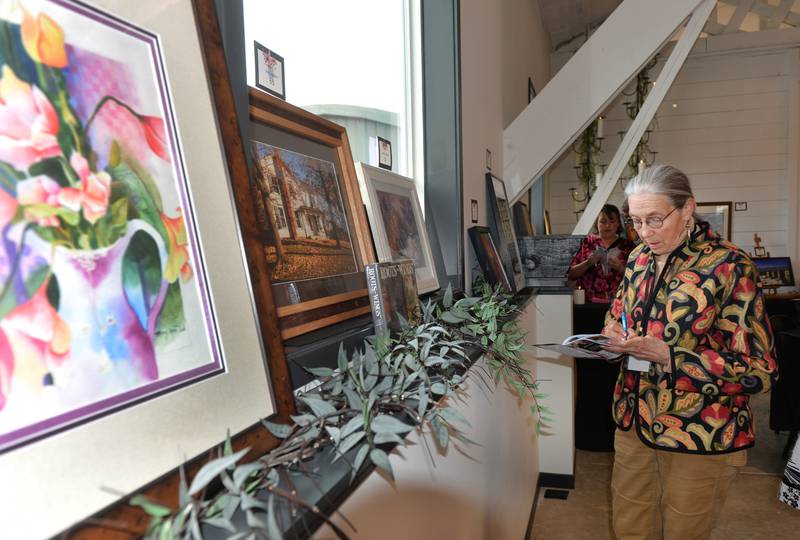 Diane Haugen  looks over the art catalog at the Art Dash, a fundraiser for Serenity Hospice & Home on Wednesday, April 10, 2024 at River's Edge in Oregon. Haugen also donated art for the fundraiser.