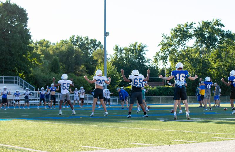 Wheaton North players warm up with jumping jacks during practice at Wheaton North on Thursday, Aug. 11, 2022.