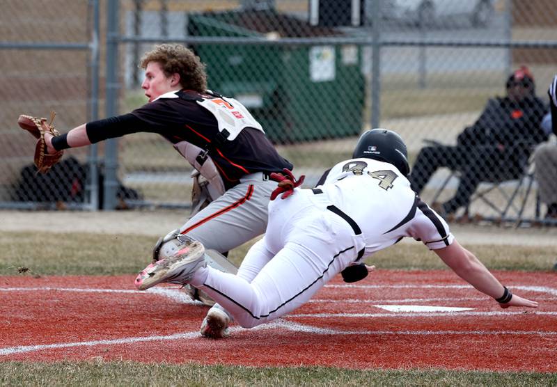 Sycamore's Davis Collie scores a run ahead of the throw to Byron catcher Kole Aken during their game Wednesday, March 26, 2025, at DeKalb High School. Sycamore’s home field was damaged in last week’s storms so today’s game was played on DeKalb’s field.