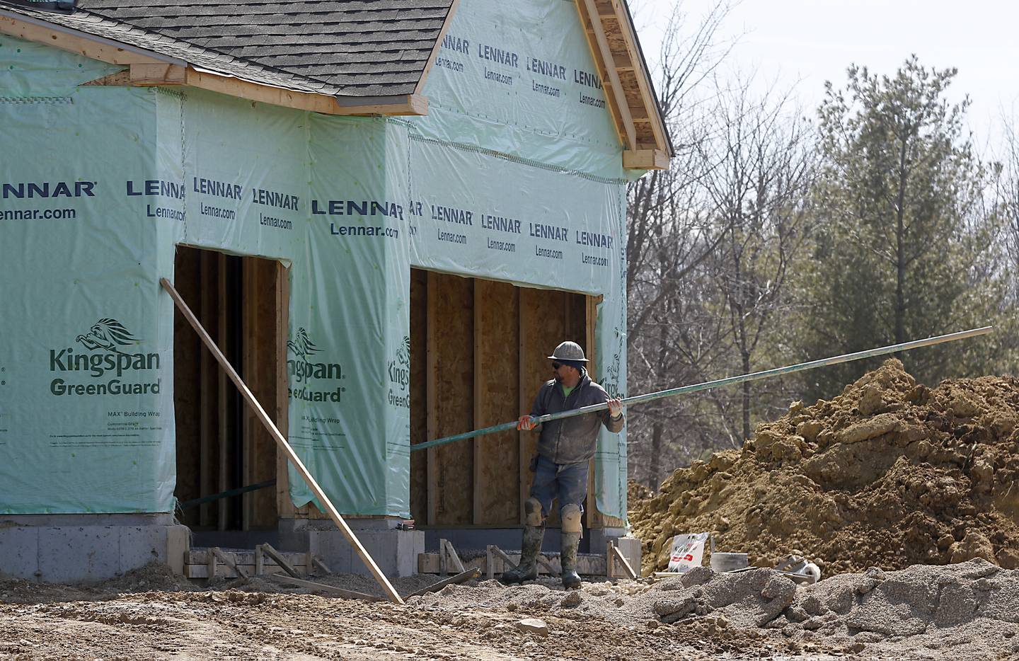 A construction worker works on the cement garage floor while building a house on Glengary Court Circle Monday, March 28, 2022, in the Woodlore Estates subdivision.