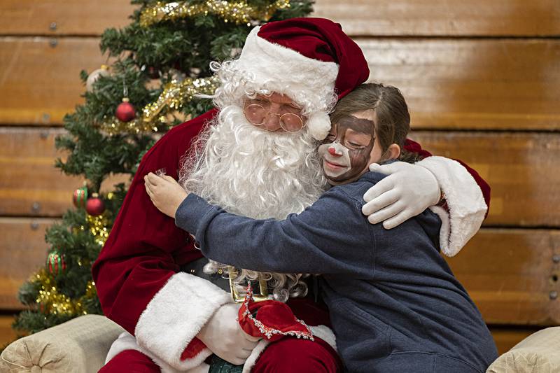 Decorated up as Rudolph, Kenzlee Abell, 10, Saturday, gives Santa a hug while visiting Tampico’s Christmas in the Country Dec. 9, 2023.