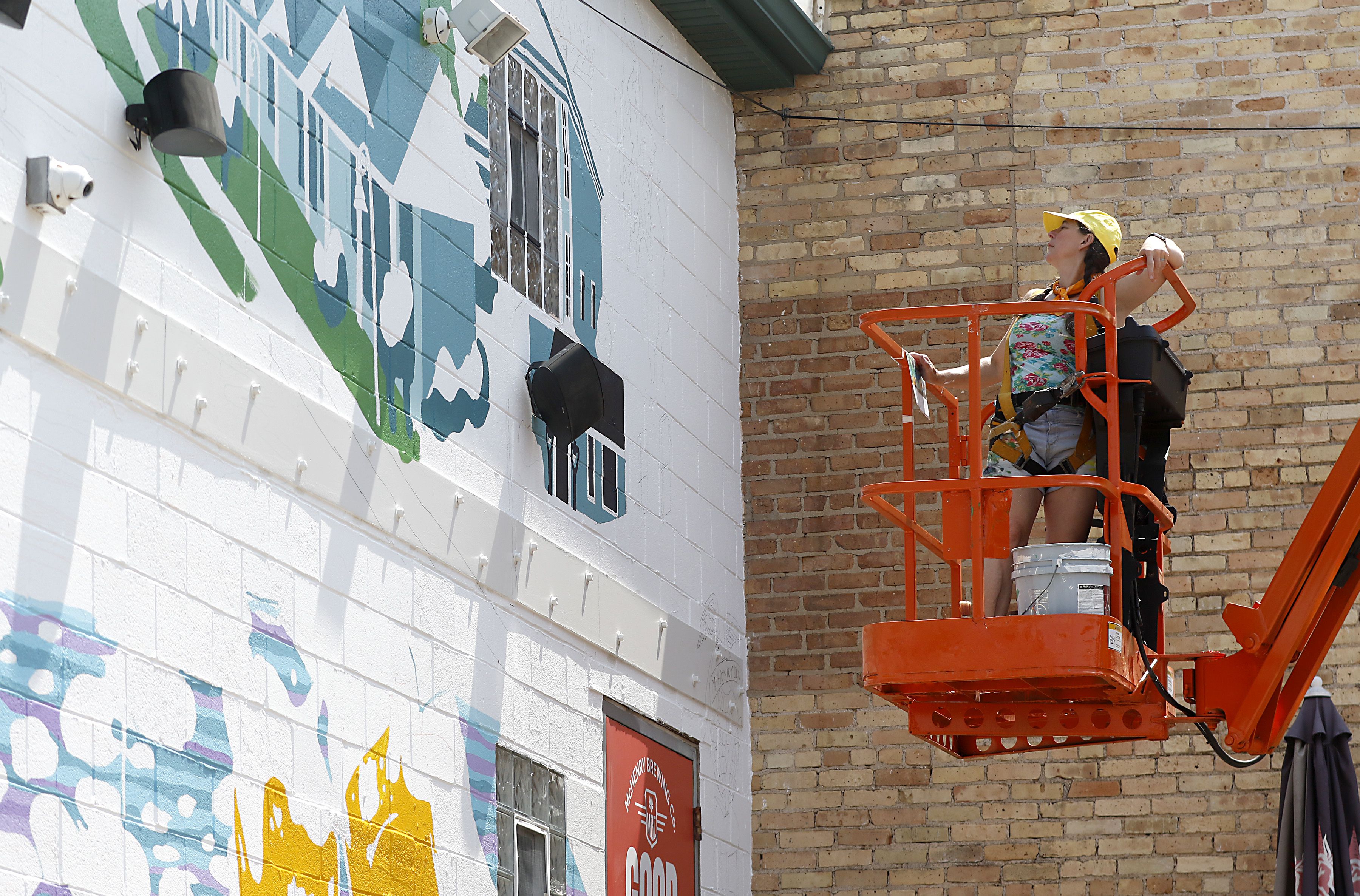 Jenny Mathews surveys her progress as she paints a mural on Thursday, June 19, 2025, on the side of the McHenry Brewing Co., in McHenry. This is one of two new McHenry murals in McHenry. 
