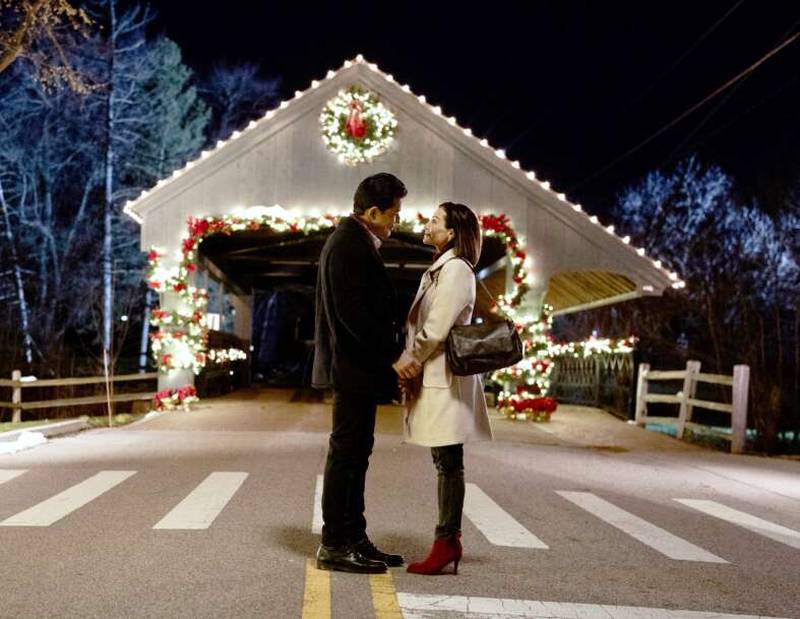 Actor Mario Lopez and his real-life wife Courtney Lopez share a kiss in front of the Long Grove Bridge in a scene from “Once Upon a Christmas Wish,” which was filmed in Long Grove.