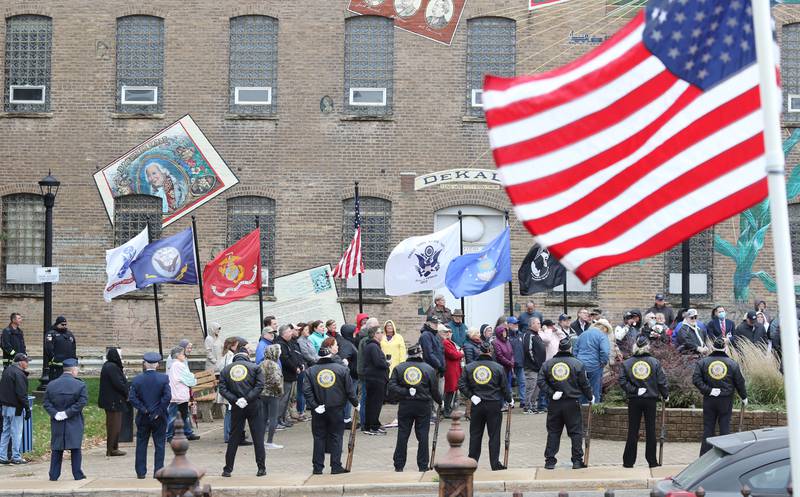 A crowd of about 100 people gather at Memorial Park to listen to speakers as the DeKalb American Legion Post 66 Honor Guard stands watch Thursday, Nov. 11, 2021, during a Veterans Day and Soldiers' and Sailors' Memorial Clock rededication ceremony in downtown DeKalb.