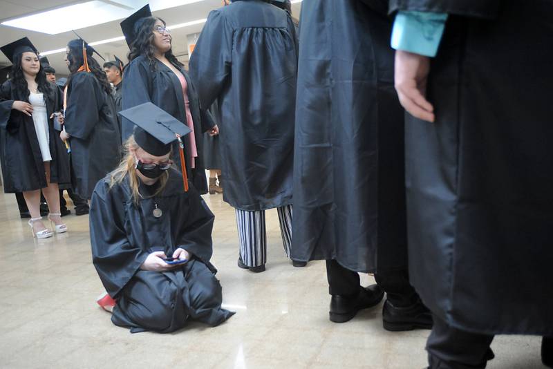 Surrounded by classmates, Miranda Noval texts from the floor of the cafeteria Saturday, May 14, 2022, during the graduation ceremony at Crystal Lake Central High School.