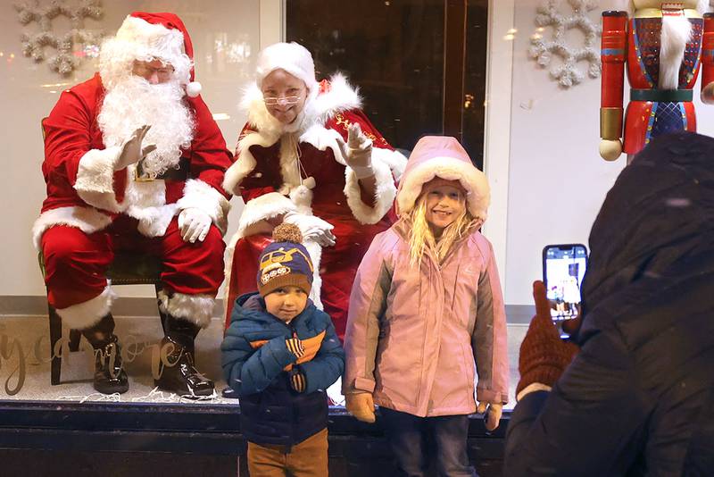 Amanda Monney, from Sycamore, takes a picture of her kids Brynlee, 6, and Hudson, 3, as they stop to say hi to Santa and Mrs. Claus in the window of Sycamore Center Friday, Nov. 18, 2022, during the Sycamore Chamber of Commerce's annual Moonlight Magic event in downtown Sycamore.