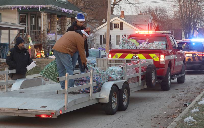 Peru Police officers deliver gifts with Santa near the intersection of 2nd and Calhoun Street as he delivers gifts to over 120 kids through the through Blue and Red Christmas for Kids on Friday, Dec. 19, 2025 in Peru. The Christmas program was established in 2013 by the Peru police and fire departments. It donates more than gifts to children in need.