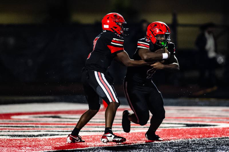 Bolingbrook Quarterback Tyson Ward hands the ball off to TJ Lewis during a game against Oswego East on Friday Oct. 31, 2025 at Bolingbrook High School