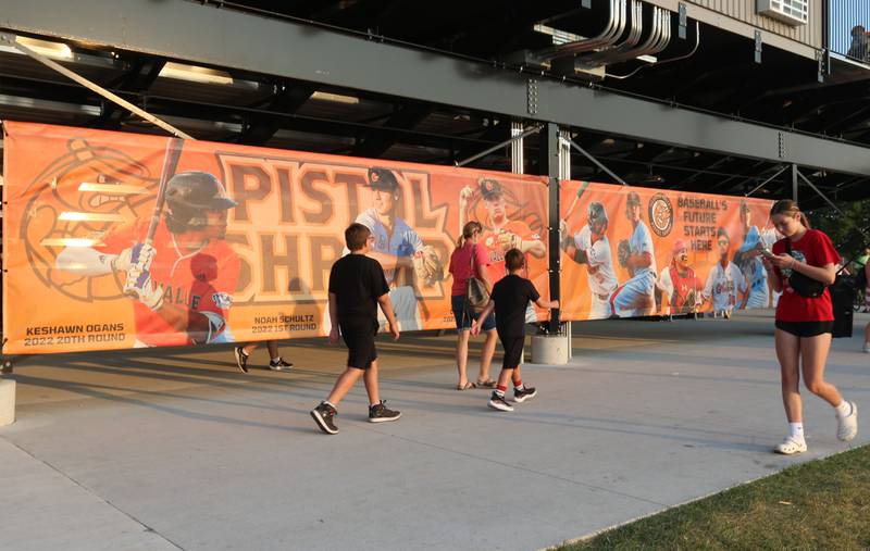 Fans walk past a Pistol Shrimp banner between innings during a home game against the Normal Cornbelters at Schweickert Stadium on Tuesday, June 20, 2023 in Peru.