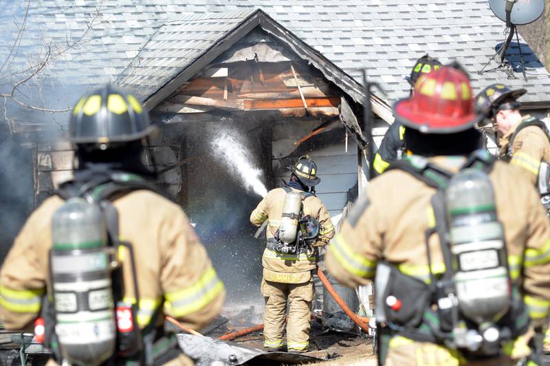 A firefighter sprays water into a house fire at 2010 S. Second St. in Daysville on Wednesday, March 12, 2025.