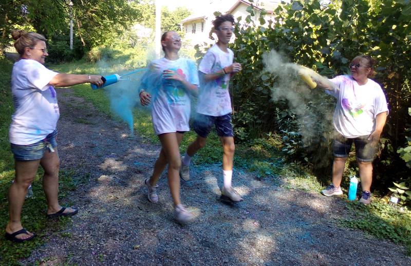 A pair of runners are greeted with color at the finish line of the Safe Journeys Color Run on Saturday, Aug. 6, 2022, at Twister Hill Park in Streator.