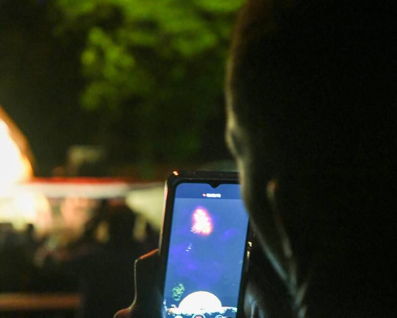 Ernest Fosu of DeKalb records the fireworks show during the annual Independence Day festivities hosted by the DeKalb Park District in Hopkins Park on Monday, July 4, 2022.