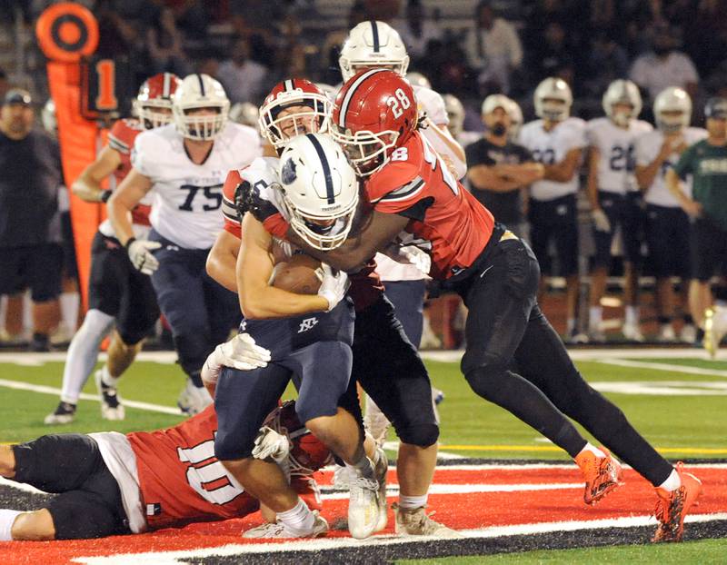 Yorkville defender Bryce Griffin (28) and fellow teammates bring down New Trier running back Jason McCarey (5) for a loss during a varsity football game at Yorkville High School on Friday, Sep. 1, 2023.