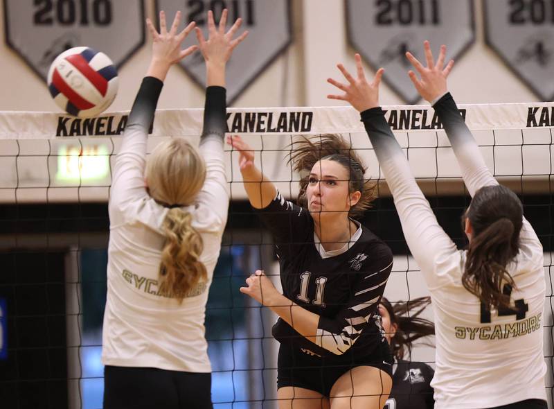 Kaneland's Natalie Remsen spikes the ball by two Sycamore blockers during their match Tuesday, Sept. 30, 2025, at Kaneland High School in Maple Park.